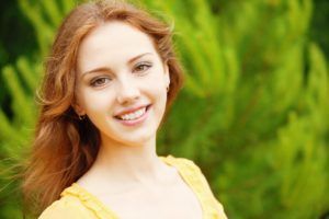 Woman smiling against a green nature background