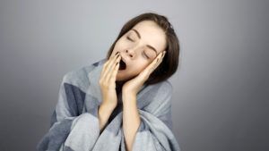 woman yawning against a grey background
